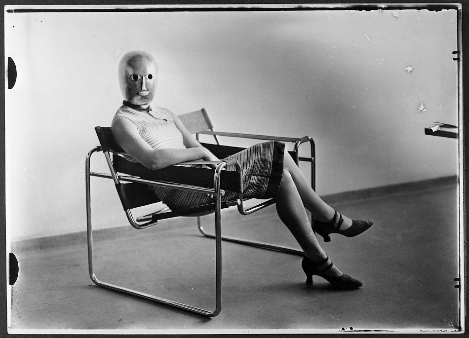 Woman wearing a theatrical mask by Oskar Schlemmer and seated on Marcel Breuer’s tubular-steel chair, c.1926. Photo: Erich Consemüller, dress material: Elisabeth Beyer-Volger, Bauhaus-Archiv Berlin / © Dr. Stephan Consemüller